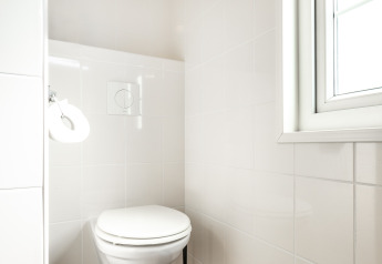 Lyst og moderne toilet med væghængt toilet på Forest Lodge, Holiday park De Witte Berg, Holland.