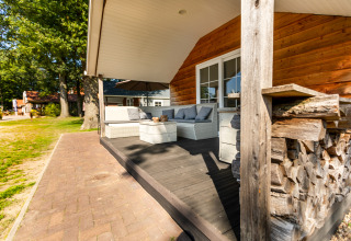 Træhytte med overdækket terrasse og udendørs siddepladser i De Witte Berg feriepark, Holland.