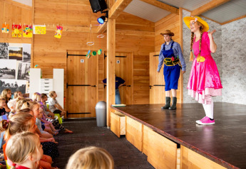 Niños viendo una obra de teatro en Forest Lodge del Holiday park De Witte Berg, Países Bajos.