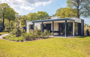 Modern vacation villa with sauna at Holiday park Ackersate in the Netherlands, surrounded by lush greenery.