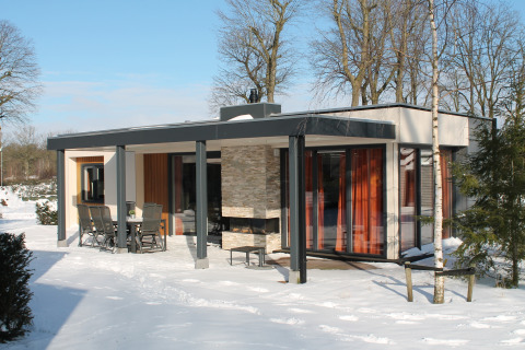 Modern vacation villa with sauna at Holiday park Ackersate in the Netherlands, surrounded by winter snow.