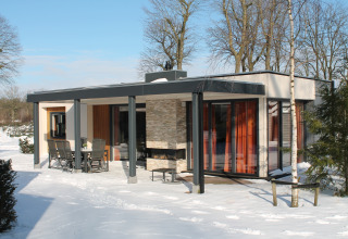 Modern vacation villa with sauna at Holiday park Ackersate in the Netherlands, surrounded by winter snow.