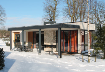 Modern vacation villa with sauna at Holiday park Ackersate in the Netherlands, surrounded by winter snow.
