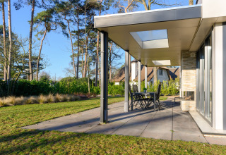 Moderne vakantievilla met overdekt terras, dakramen en tuin op vakantiepark Ackersate in Nederland.