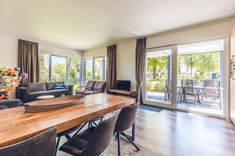 Lyst og rummeligt opholdsområde i ferievilla med store vinduer og udsigt til terrasse i Holiday park Ackersate.