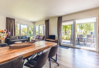 Ruime en lichte woonkamer met zicht op het terras in vakantievilla met sauna op Holiday park Ackersate.
