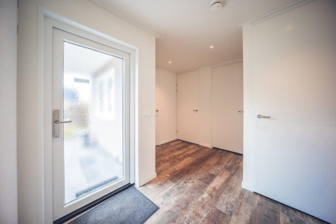 Entrance hallway of a vacation villa with wooden floor and white doors at Holiday park Ackersate, Netherlands.
