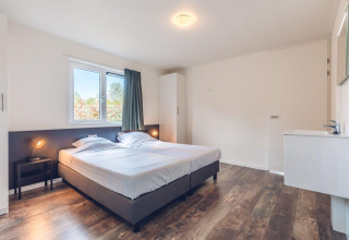 Dormitorio luminoso y espacioso con dos camas individuales en villa vacacional con sauna en Holiday park Ackersate, Países Bajos.
