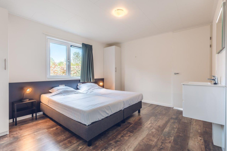 Dormitorio luminoso y espacioso con dos camas individuales en villa vacacional con sauna en Holiday park Ackersate, Países Bajos.