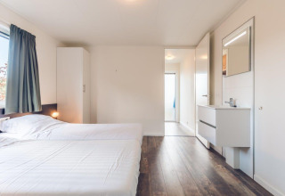 Slaapkamer met twee losse bedden, kast en wastafel in Vacation villa + sauna, Ackersate, Nederland.