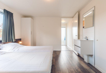 Habitación luminosa con dos camas individuales, armario y lavabo en Vacation villa + sauna, Ackersate.