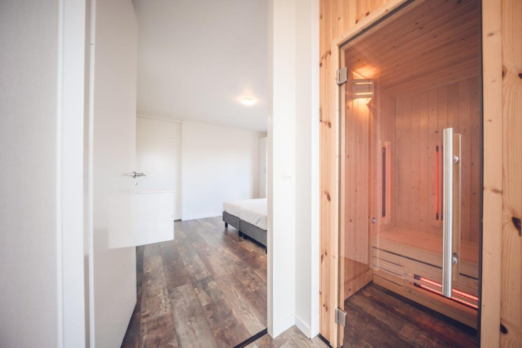 Villa vacacional moderna con sauna y suelo de madera en Holiday park Ackersate, Países Bajos, vista al dormitorio.