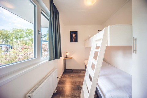 Bright room with bunk bed, large window and nature view at Vacation Villa + Sauna, Holiday Park Ackersate, Netherlands.