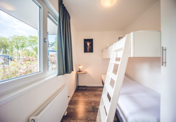 Helles Zimmer mit Etagenbett, großem Fenster und Blick ins Grüne in der Ferienanlage Ackersate, Niederlande.