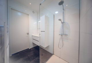 Baño moderno con ducha acristalada y baldosas blancas en Vacation villa + sauna en Holiday park Ackersate.
