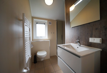 Bagno moderno con lavabo bianco, WC e grande specchio al Kids cottage di Kaatsheuvel, Paesi Bassi.