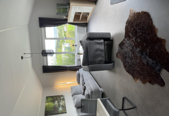 Sala moderna en Chalet Brilon, Camping & Ferienpark Brilon, Alemania, con ventana y vista al bosque.