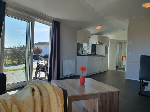 Lichte woonkamer en keuken in Chalet Brilon op Camping & Ferienpark Brilon, Duitsland, zicht op tuin.