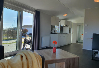 Lichte woonkamer en keuken in Chalet Brilon op Camping & Ferienpark Brilon, Duitsland, zicht op tuin.