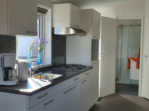 Cocina moderna en Chalet Brilon con estufa de gas, fregadero, cafetera y vista al baño en Alemania.