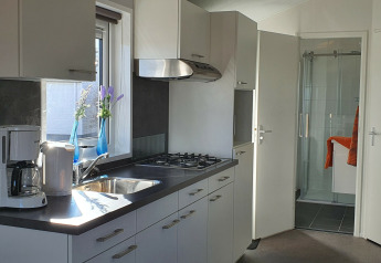 Cuisine moderne du Chalet Brilon avec plaque gaz, évier, cafetière et vue sur la salle de bain en Allemagne.