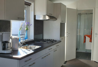 Cocina moderna en Chalet Brilon con estufa de gas, fregadero, cafetera y vista al baño en Alemania.