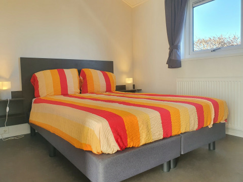 Dormitorio con cama doble y ropa de cama a rayas de colores en Chalet Brilon en Camping & Ferienpark Brilon en Alemania.