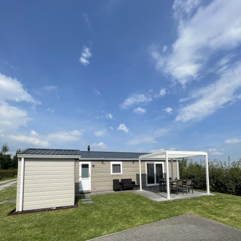 Chalet Brilon en Camping & Ferienpark Brilon, Alemania, con terraza y zona de estar al aire libre bajo el cielo azul.