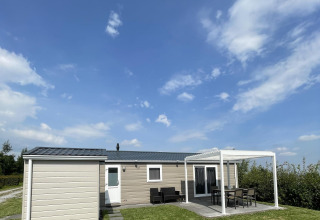 Chalet Brilon en Camping & Ferienpark Brilon, Alemania, con terraza y zona de estar al aire libre bajo el cielo azul.