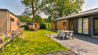 Vue extérieure d’un lodge de luxe avec sauna à Drentse Weelde, Pays-Bas, avec terrasse et jardin moderne.