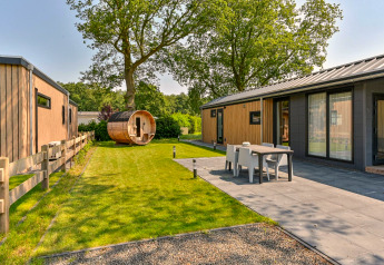 Buitenaanzicht van een luxelodge met sauna bij Drentse Weelde in Nederland, met terras en groene tuin.
