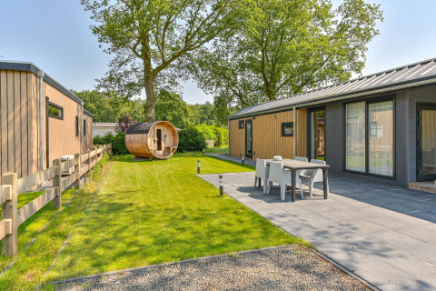 Buitenzicht op een luxelodge met sauna bij Drentse Weelde in Nederland, met terras en groene tuin.
