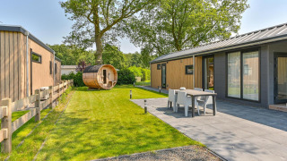 Buitenzicht op een luxelodge met sauna bij Drentse Weelde in Nederland, met terras en groene tuin.