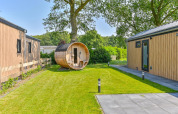 Udendørsfoto af en rummelig lodge med træfacader og en rund sauna i haven ved Drentse Weelde, Holland.