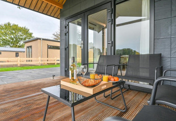 Terraza exterior de una lujosa cabaña en Drentse Weelde, Países Bajos, con vino, snacks y asientos modernos.
