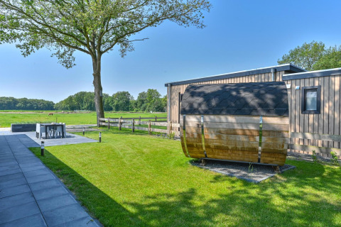 Vista exterior de una cabaña de lujo con sauna en Drentse Weelde, Países Bajos, rodeada de jardines.