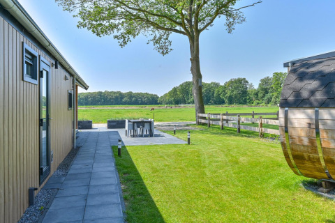 Espace extérieur du Luxury lodge + sauna à Drentse Weelde, Pays-Bas, avec terrasse, pelouse et vue sur champ.