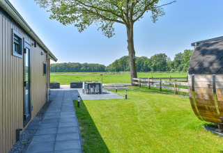 Espace extérieur du Luxury lodge + sauna à Drentse Weelde, Pays-Bas, avec terrasse, pelouse et vue sur champ.
