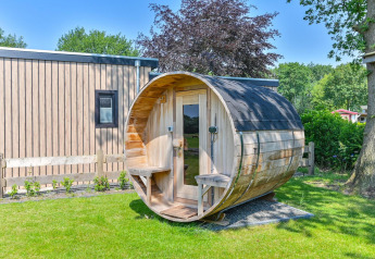 Lodge de luxe avec sauna en forme de tonneau à l’extérieur à Drentse Weelde, Pays-Bas, par temps ensoleillé.