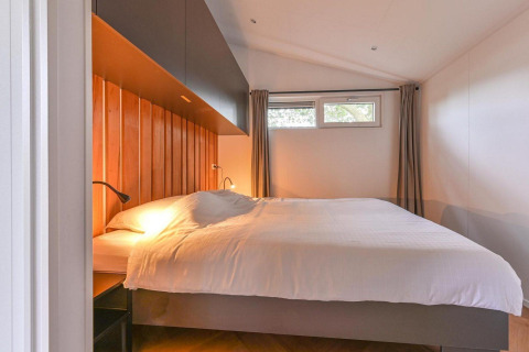 Dormitorio en la Luxury lodge + sauna en Drentse Weelde, Países Bajos, con cama grande y decoración moderna.