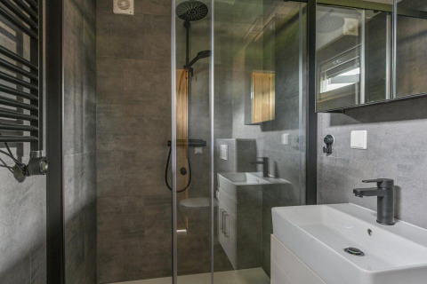 Baño moderno en Luxury lodge con ducha de lluvia, puerta de cristal y grifería negra en Drentse Weelde, Países Bajos.