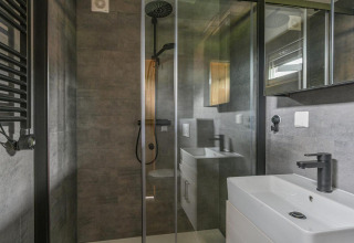 Modernes Badezimmer in der Luxury Lodge mit Regendusche, Glaswand und schwarzer Armatur in Drentse Weelde, Niederlande.