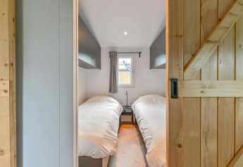 Modern twin bedroom with two single beds, wood sliding door, and window at Luxury lodge + sauna, Drentse Weelde.