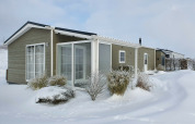 Chalet Marron en Camping & Ferienpark Brilon, Alemania, en invierno con nieve y arbustos helados alrededor.