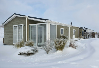 Chalet Marron en Camping & Ferienpark Brilon, Alemania, en invierno con nieve y arbustos helados alrededor.