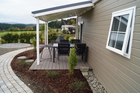 Overdekt terras aan Chalet Marron op Camping & Ferienpark Brilon in Duitsland, met tuinmeubilair en uitzicht.