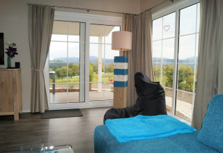 Wohnzimmer im Chalet Marron, Camping & Ferienpark Brilon, mit Panoramablick auf deutsche Hügel.