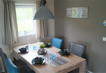 Comedor en el Chalet Marron en Camping & Ferienpark Brilon, Alemania, con mesa puesta moderna.