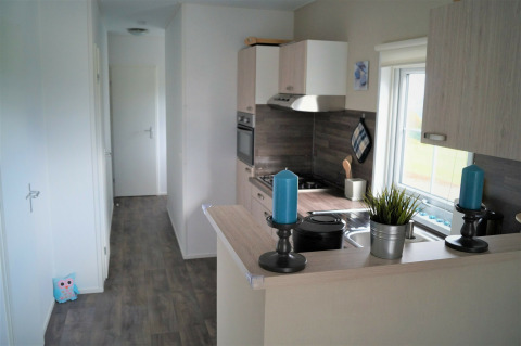 Lichte, moderne keuken van Chalet Marron in Camping & Ferienpark Brilon, Duitsland, met blauwe kaarsen.