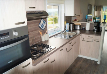 Cocina moderna con horno, estufa, fregadero y cafetera en Chalet Marron, Camping & Ferienpark Brilon, Alemania.